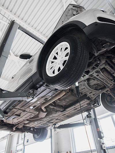 Man sieht auf den Unterboden eines Autos auf einer Hebebühne