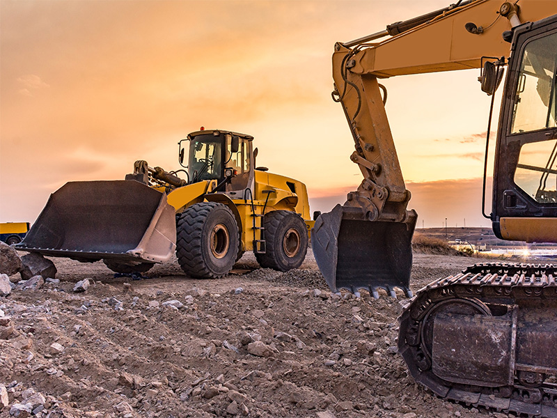 belis-oberflaechentechnik-branchen-landundbaumaschinen Zwei gelbe Baumaschinen auf Schotter